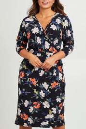 Model Monique wearing size 14 of the Belle Heather Floral Wrap Dress in colour Florals (Blue), from the front, cropped image
