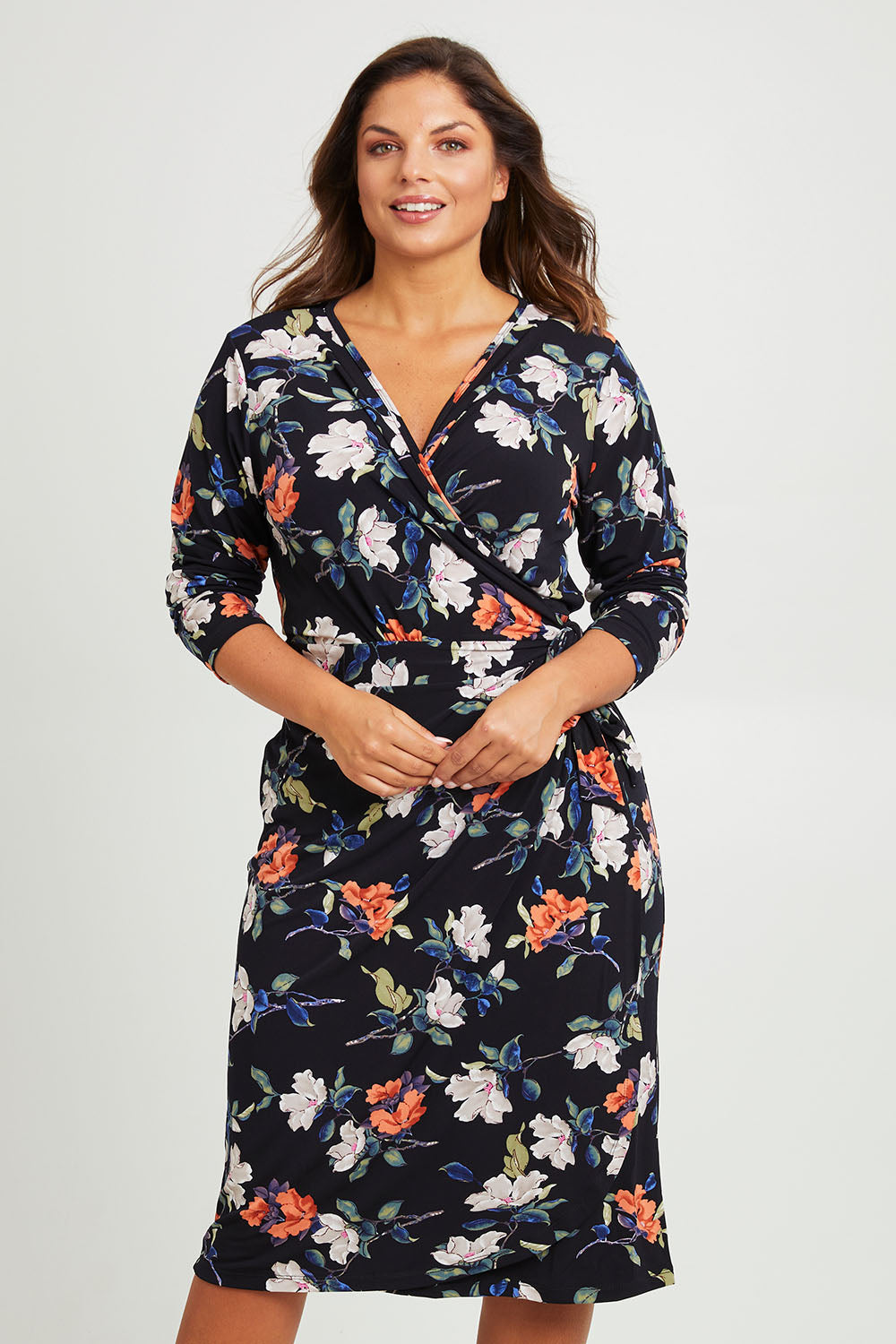 Model Monique wearing size 14 of the Belle Heather Floral Wrap Dress in colour Florals (Blue), from the front, cropped image