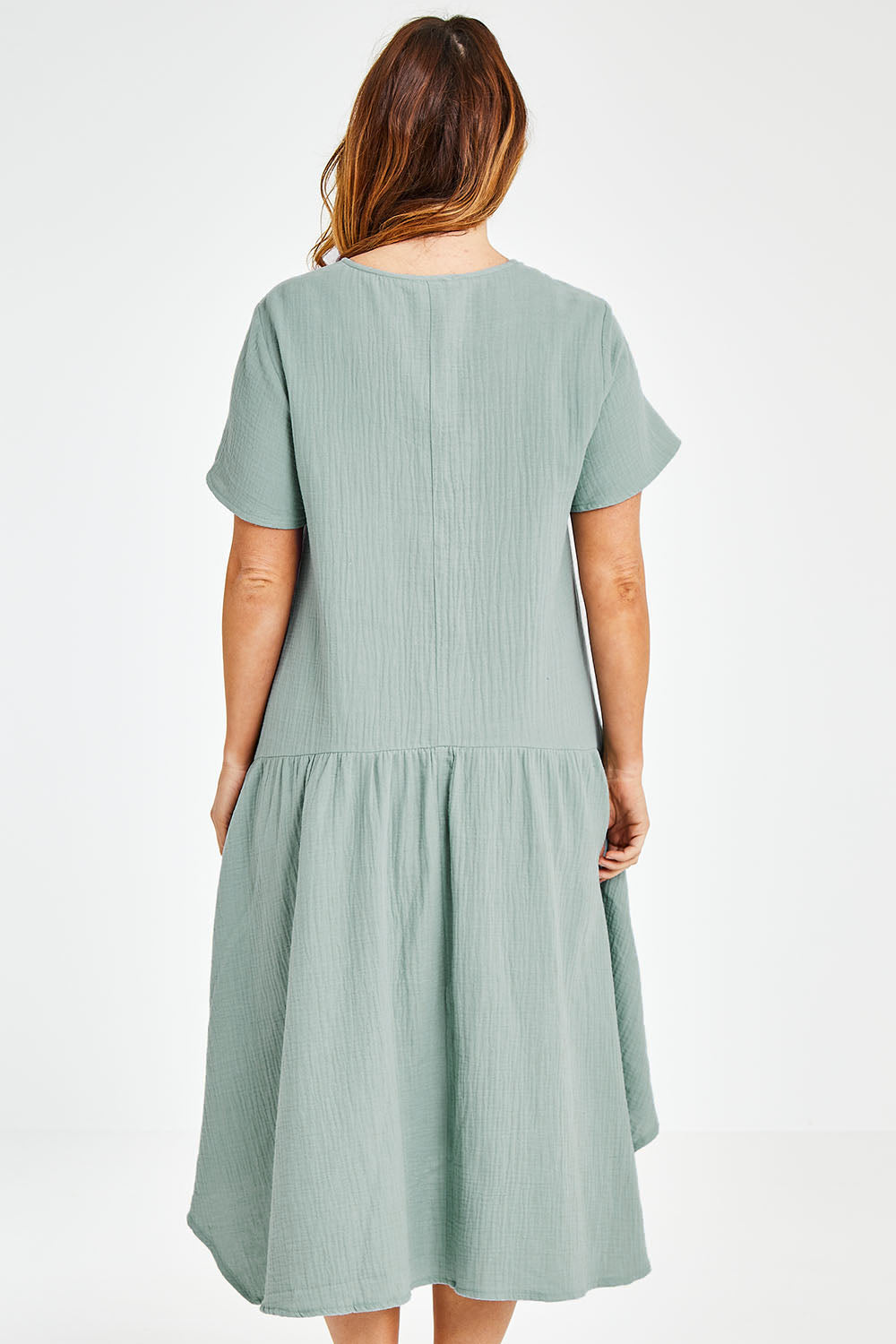Model Laura wearing size 12 of the Belle Angled Hem Dress in colour Sage (Green), from the back