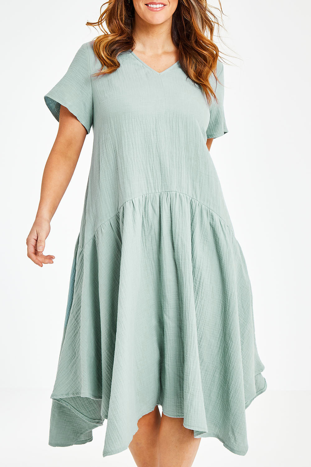 Model Laura wearing size 12 of the Belle Angled Hem Dress in colour Sage (Green), from the front, cropped image