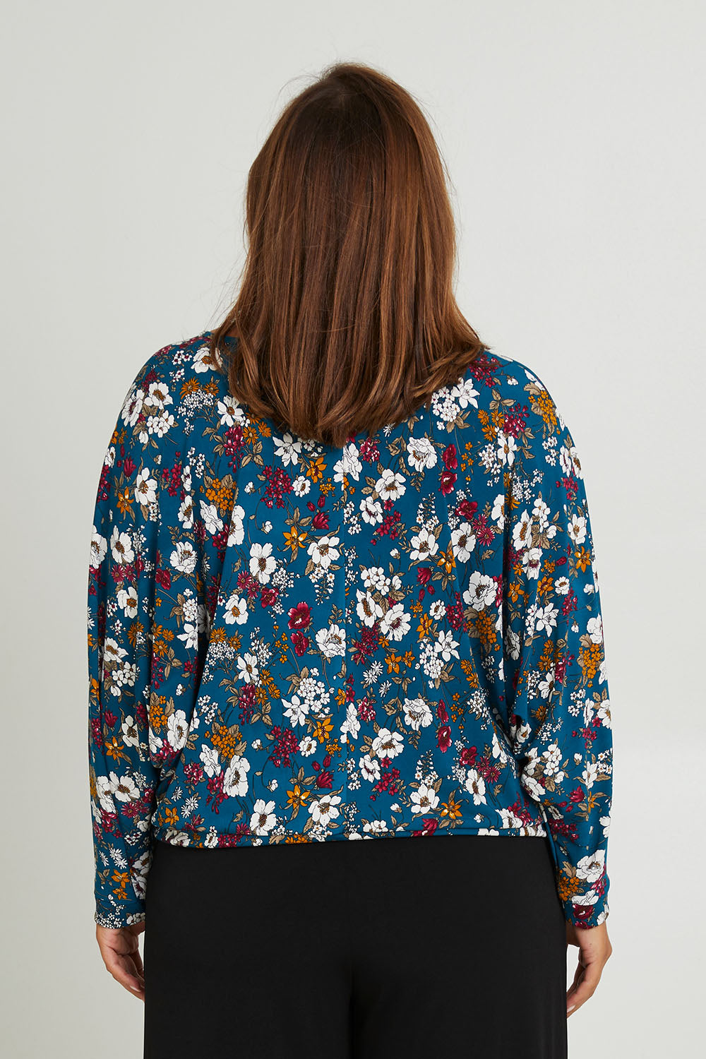Model Monique wearing size 14 of the Belle Hip Knot Printed Tee in colour Tealfleur (Green), from the back