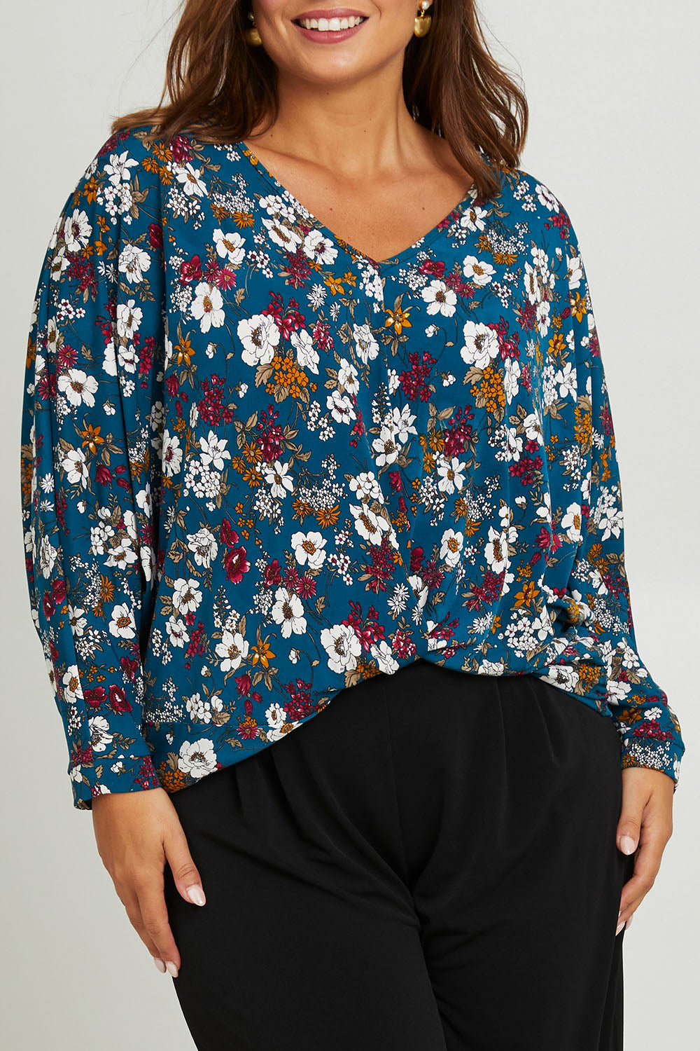Model Monique wearing size 14 of the Belle Hip Knot Printed Tee in colour Tealfleur (Green), from the front, cropped image