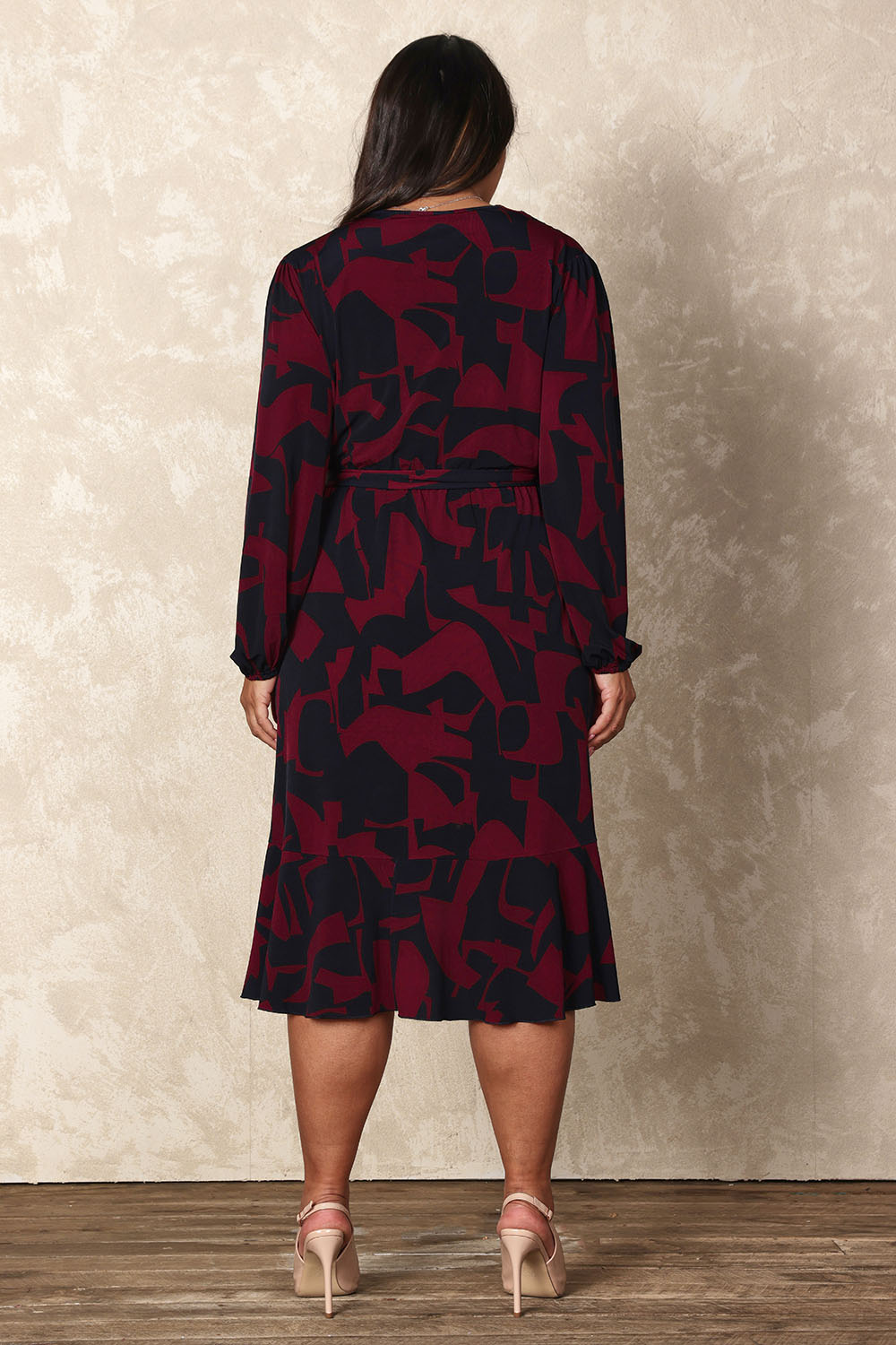 Model Ashleigh wearing size 16 of the Belle Printed Long Sleeve Mock Wrap Dress in colour Winenavy (Blue), from the back