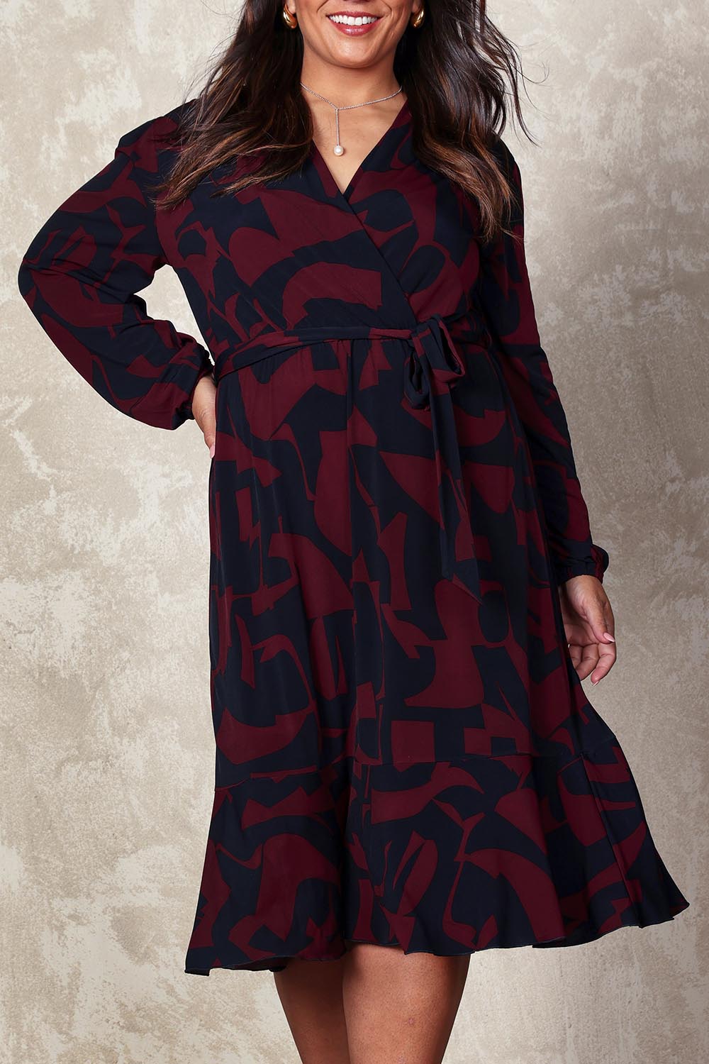 Model Ashleigh wearing size 16 of the Belle Printed Long Sleeve Mock Wrap Dress in colour Winenavy (Blue), from the front, cropped image