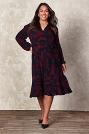 Model Ashleigh wearing size 16 of the Belle Printed Long Sleeve Mock Wrap Dress in colour Winenavy (Blue), from the front, showing the whole outfit