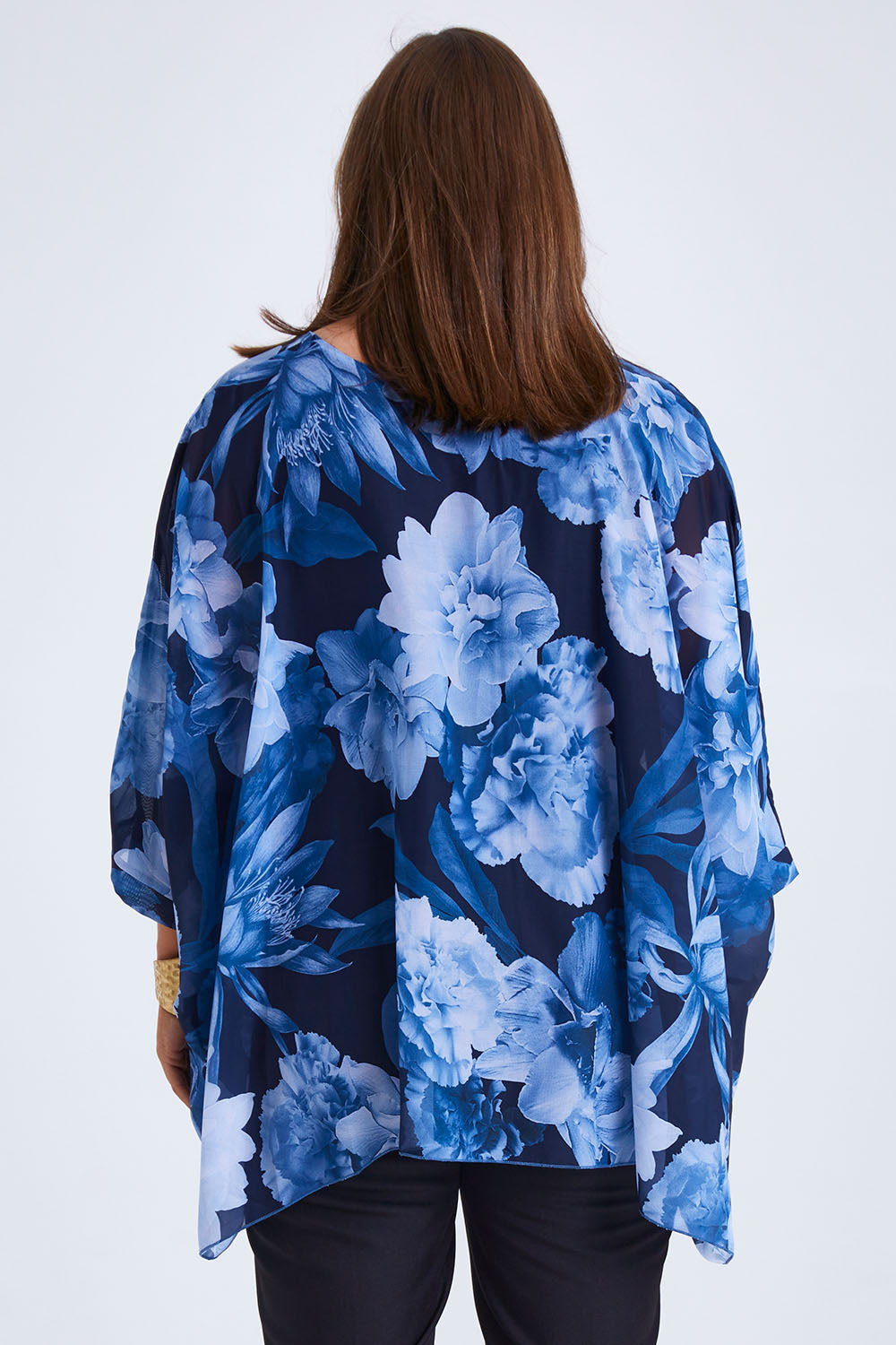 Model Monique wearing size 14 of the Belle Chiffon Overlay Top in colour Bluefloral (Blue), from the back