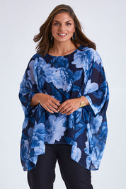 Model Monique wearing size 14 of the Belle Chiffon Overlay Top in colour Bluefloral (Blue), from the front, cropped image