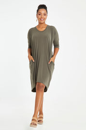 Model Noli wearing size 14 of the Belle High Low Easy Wear Dress in colour Khaki (Green), from the front, showing the whole outfit