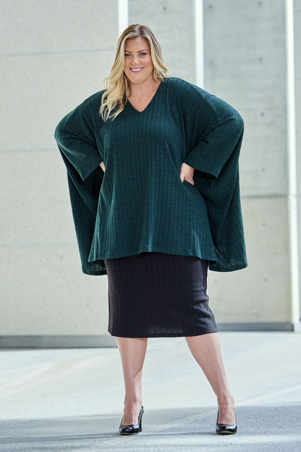 Model Caitlin wearing size 18 of the Belle Classic Knit Midi Skirt in colour Black (Black), from the front, showing the whole outfit