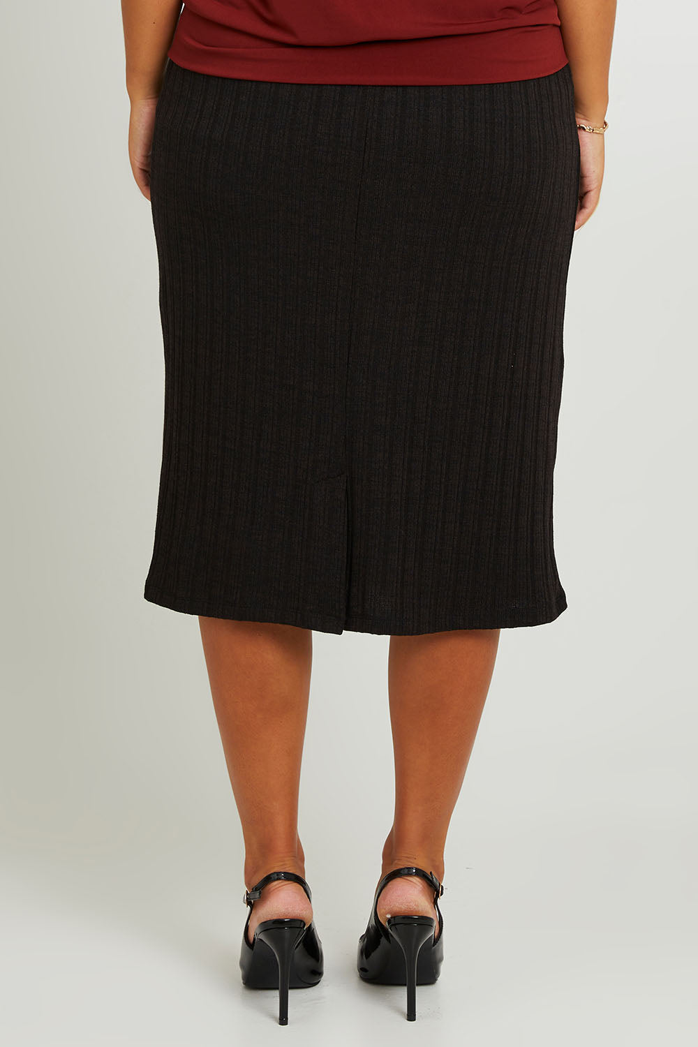 Model Monique wearing size 14 of the Belle Classic Knit Midi Skirt in colour Black (Black), from the back