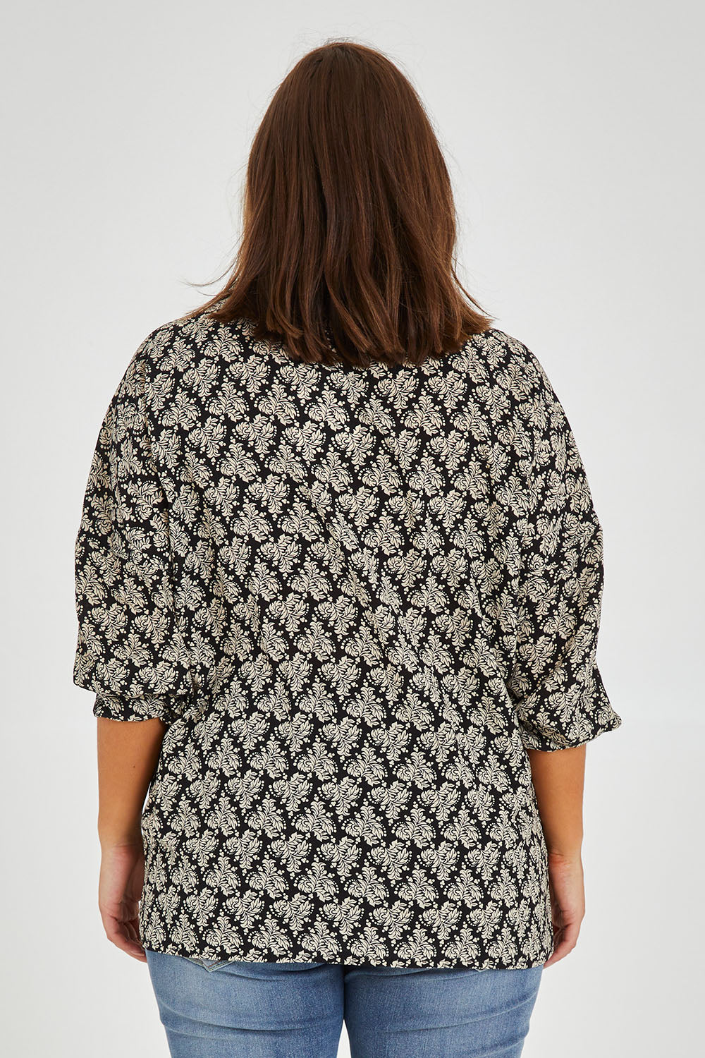 Model Monique wearing size 14 of the Belle Batwing Printed Shirt in colour Blackivory (Black), from the back