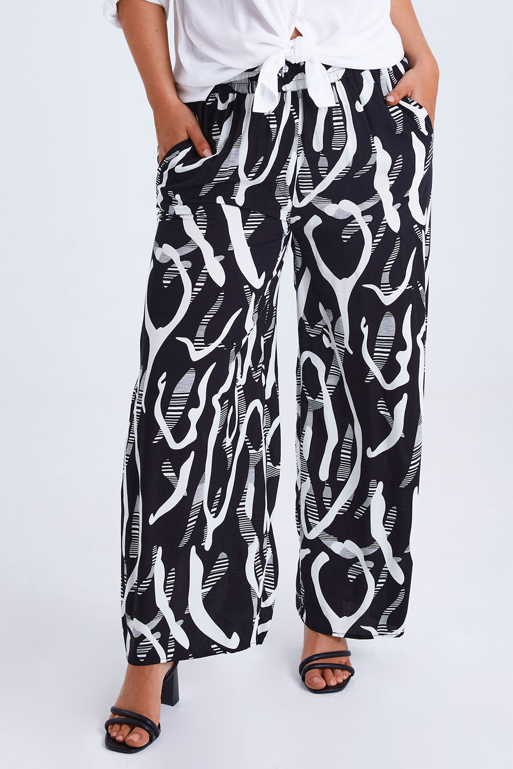 Model Monique wearing size 14 of the Belle Relaxed Wide Leg Pull On Pant in colour Blackivory (Black), from the front, cropped image