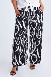 Model Monique wearing size 14 of the Belle Relaxed Wide Leg Pull On Pant in colour Blackivory (Black), from the front, cropped image