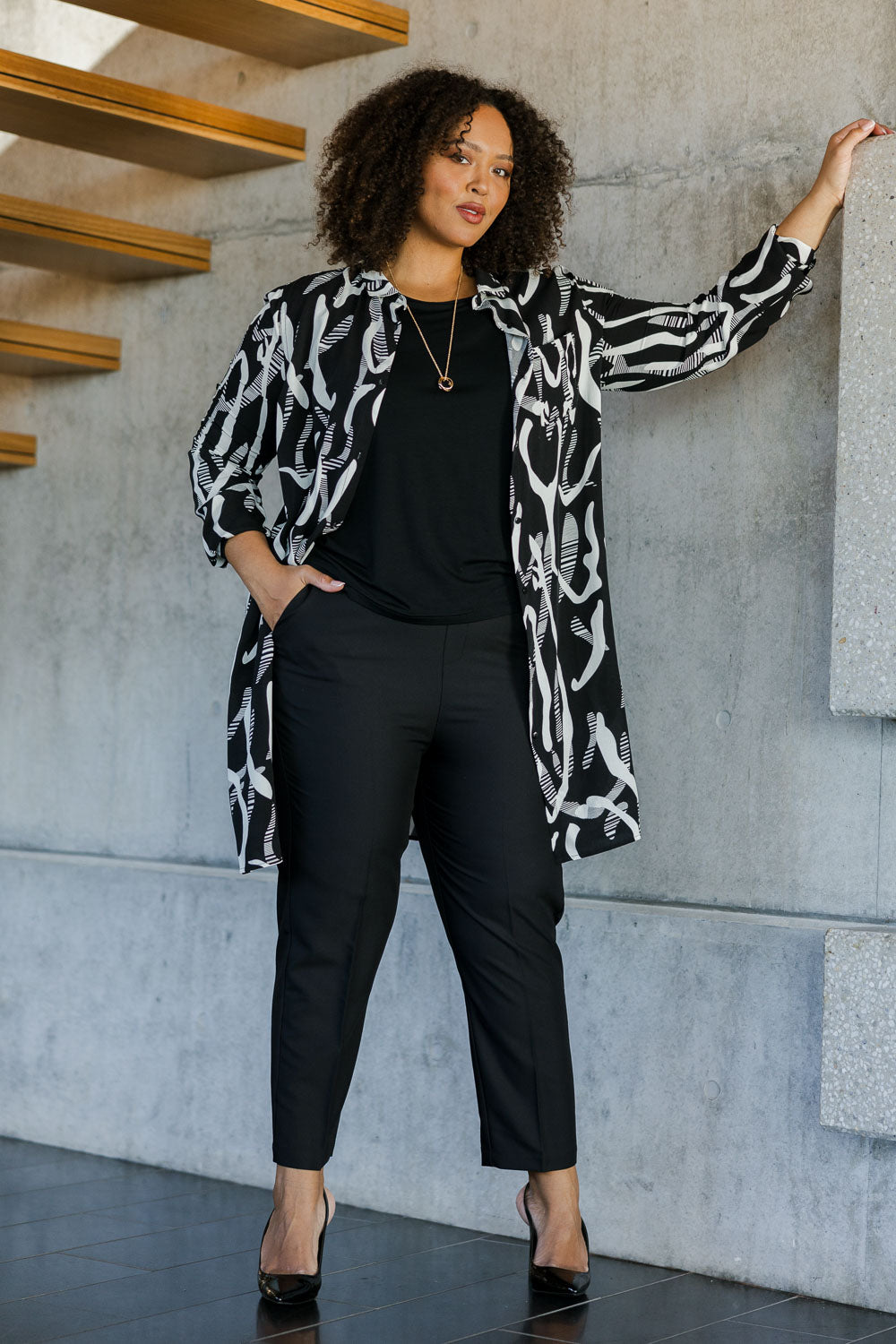 Model Alexis wearing size 18 of the Belle Pull On Tailored Pant in colour Black (Black), from the front, showing the whole outfit