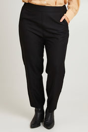 Model Laura wearing size 14 of the Belle Pull On Tailored Pant in colour Black (Black), from the front, cropped image