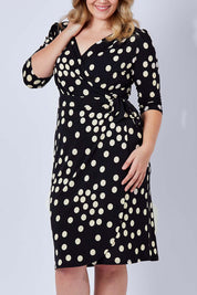 Model Kate wearing size 16 of the Belle Spot Print Wrap Dress in colour Black (Black), from the front, cropped image
