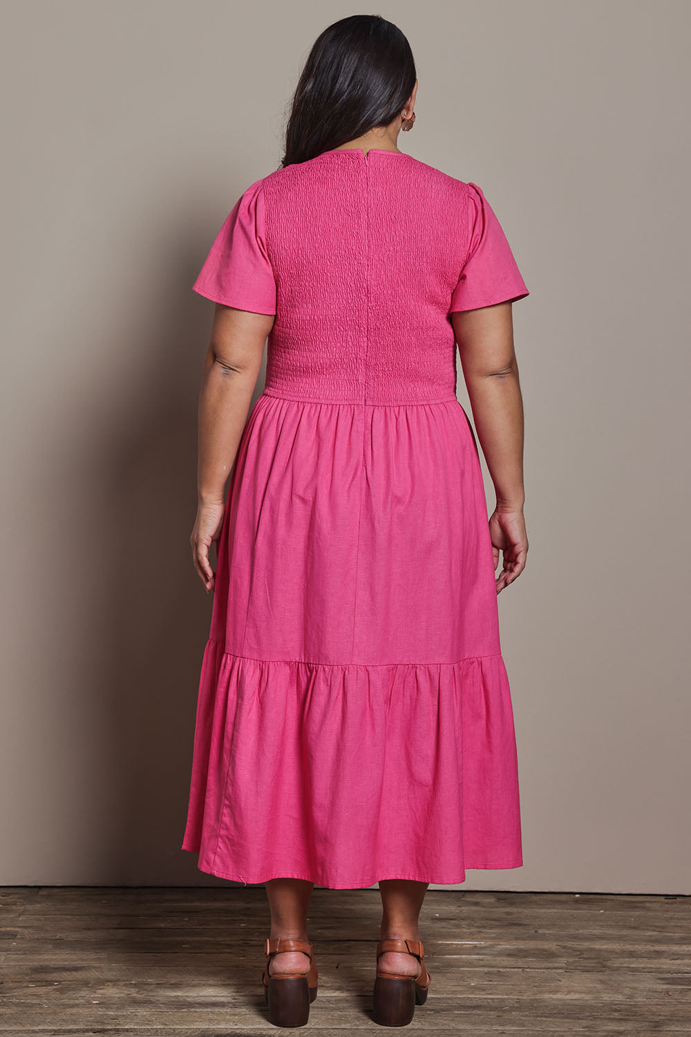 Model Ashleigh wearing size 16 of the Belle Cotton Shirred Bodice Dress in colour Candypink (Pink), from the back