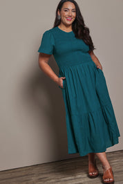 Model Ashleigh wearing size 16 of the Belle Cotton Shirred Bodice Dress in colour Deepocean (Green), from the front, showing the whole outfit
