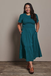 Model Ashleigh wearing size 16 of the Belle Cotton Shirred Bodice Dress in colour Deepocean (Green), from the front, showing the whole outfit