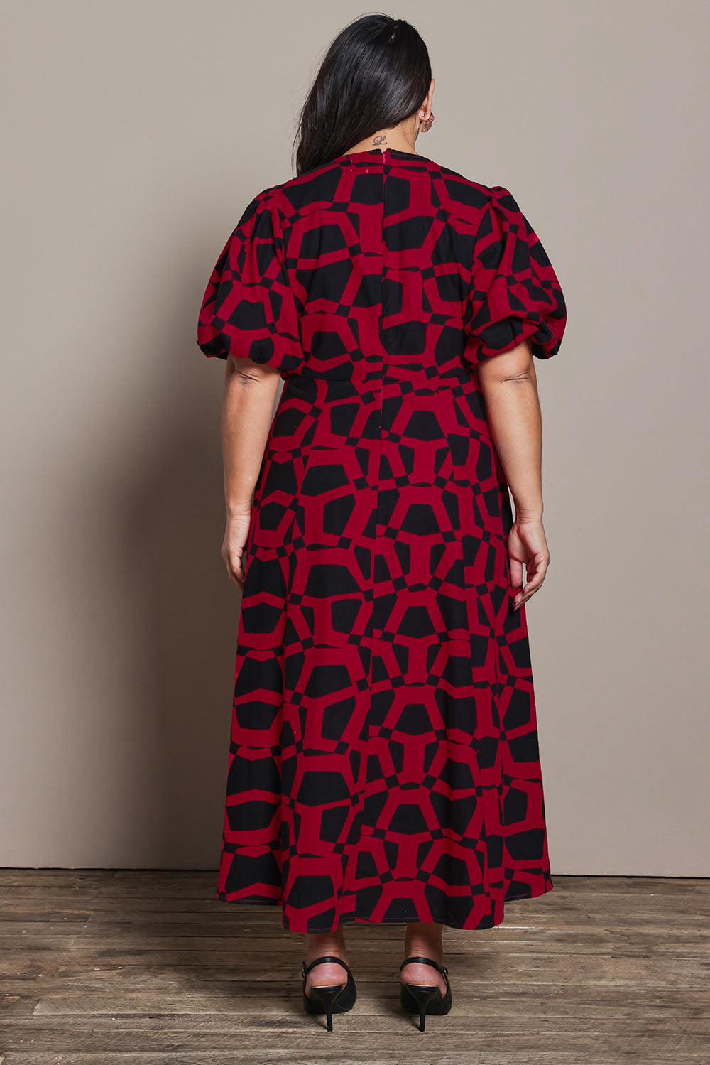 Model Ashleigh wearing size 16 of the Belle Printed Twist Knot Detail Cotton Dress in colour Blackrasp (Black), from the back