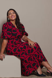 Model Ashleigh wearing size 16 of the Belle Printed Twist Knot Detail Cotton Dress in colour Blackrasp (Black), from the front, showing the whole outfit