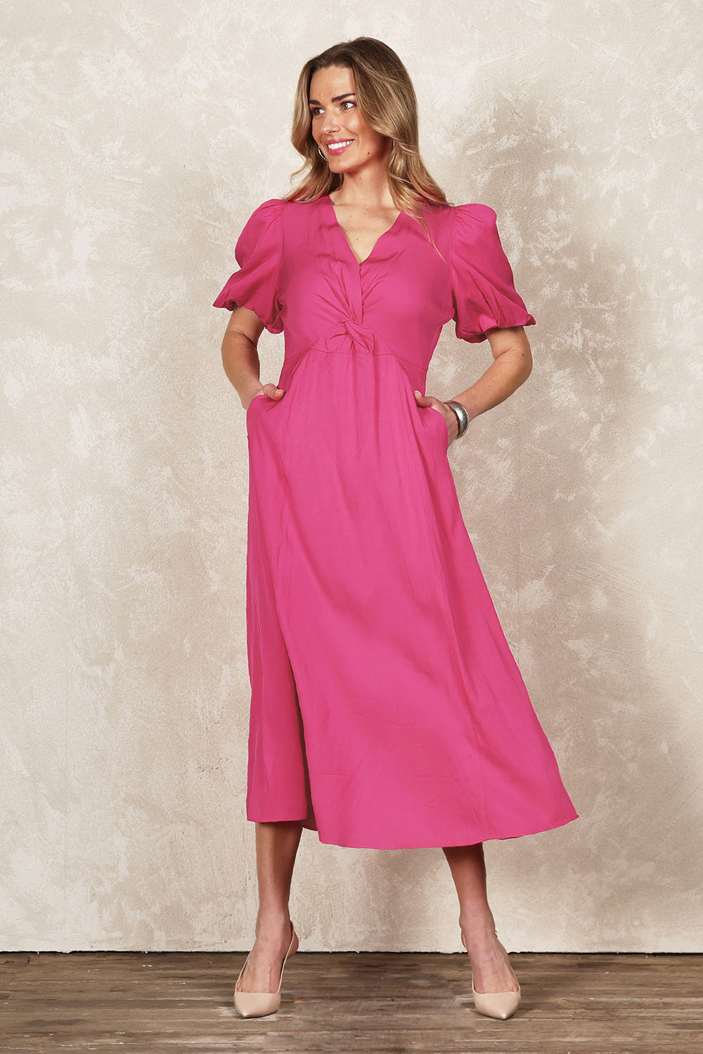 Model Olivia wearing size 10 of the Belle Twist Knot Detail Cotton Dress in colour Candypink (Pink), from the front, showing the whole outfit