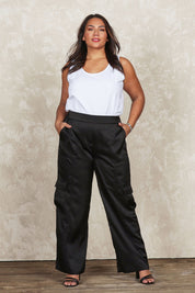 Model Jane wearing size 16 of the Belle Pull On Satin Cargo Pants in colour Black (Black), from the front, showing the whole outfit