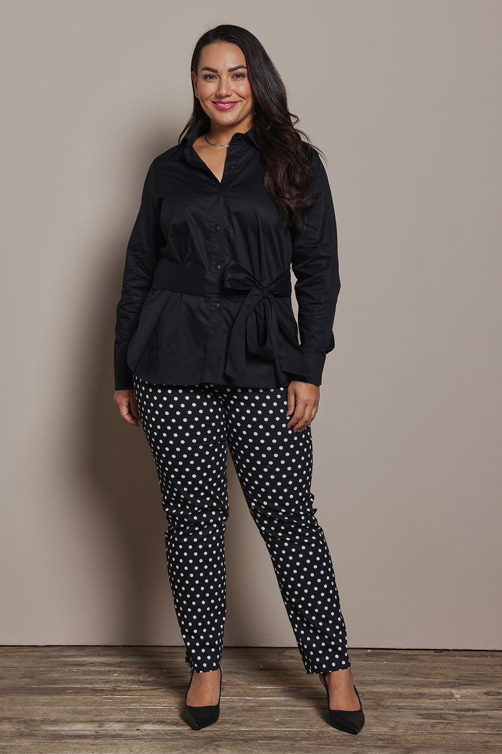 Model Ashleigh wearing size 16 of the Belle Tie Waist Cotton Shirt in colour Black (Black), from the front, showing the whole outfit