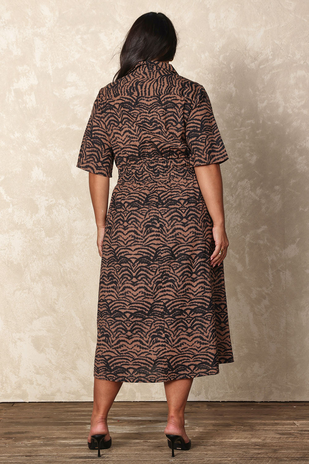 Model Ashleigh wearing size 16 of the Belle Printed Cotton Shirred Dress With Pockets in colour Blackcamel (Black), from the back