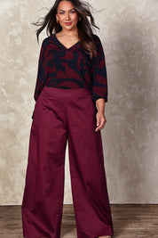 Model Ashleigh wearing size 16 of the Belle Easywear V Neck Pop Over Top in colour Winenavy (Blue), from the front, showing the whole outfit