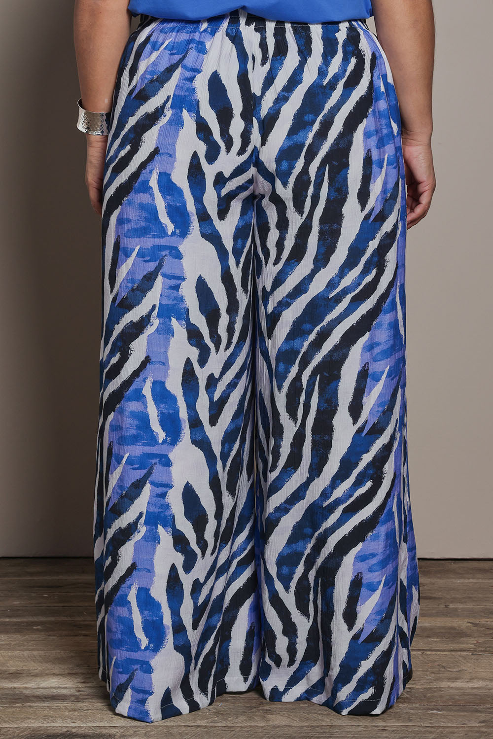 Model Ashleigh wearing size 16 of the Belle Pull On Printed Wide Leg Pant with Pockets in colour Bluezebra (Blue), from the back