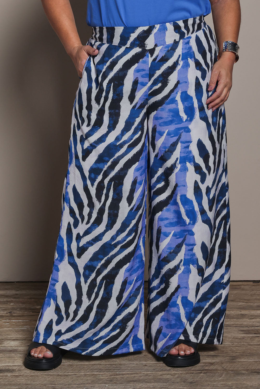 Model Ashleigh wearing size 16 of the Belle Pull On Printed Wide Leg Pant with Pockets in colour Bluezebra (Blue), from the front, cropped image
