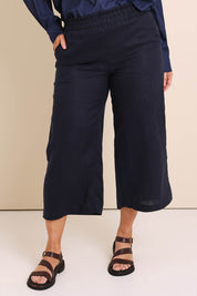 Model Lauraw wearing size 14 of the Belle Easy Wear Linen Pant – Navy in colour Navy, in a cropped view