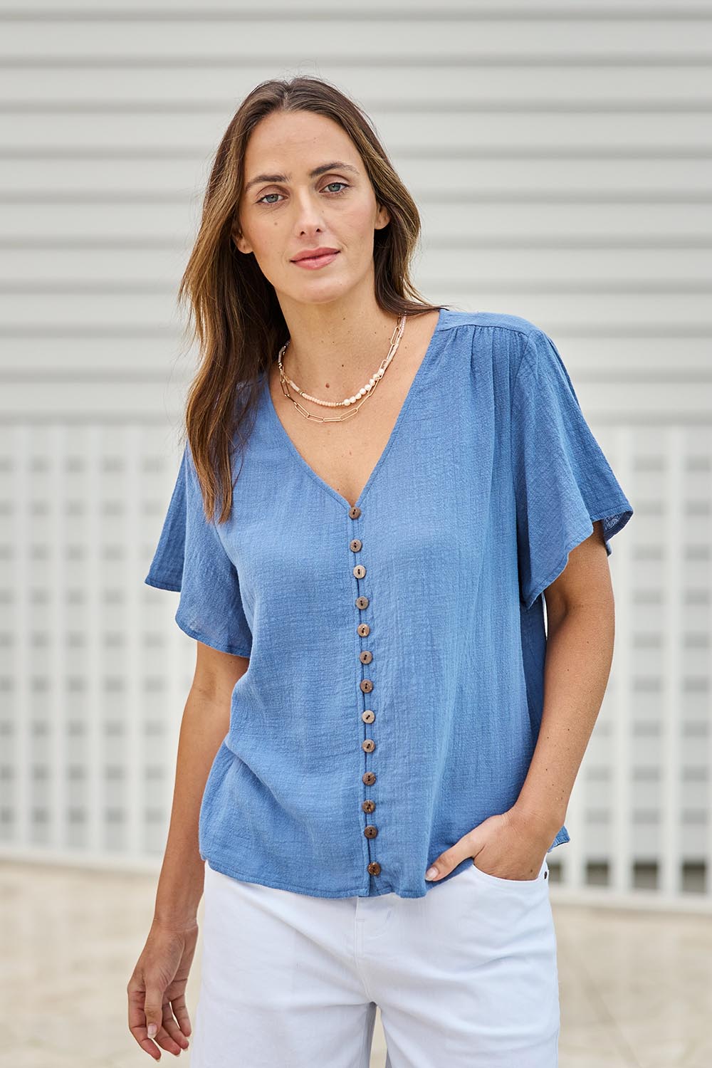 Model Tegand wearing size 10 of the Cute As A Button Blouse – Denim in colour Denim, in a cropped view