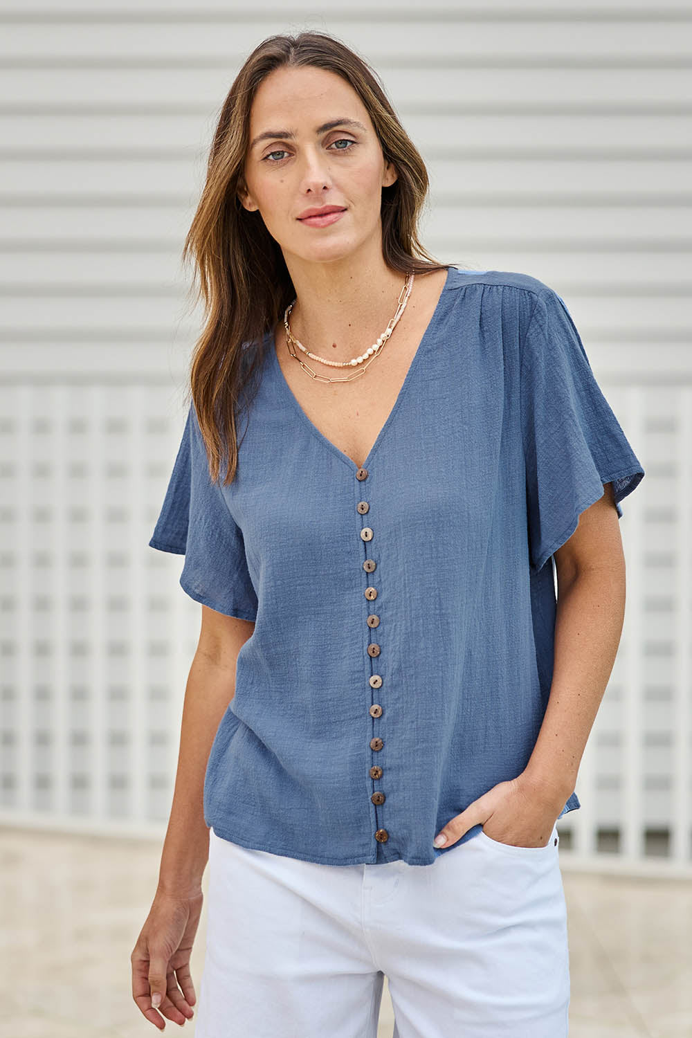 Model Tegand wearing size 10 of the Cute As A Button Blouse – Denim in colour Denim, in a cropped view