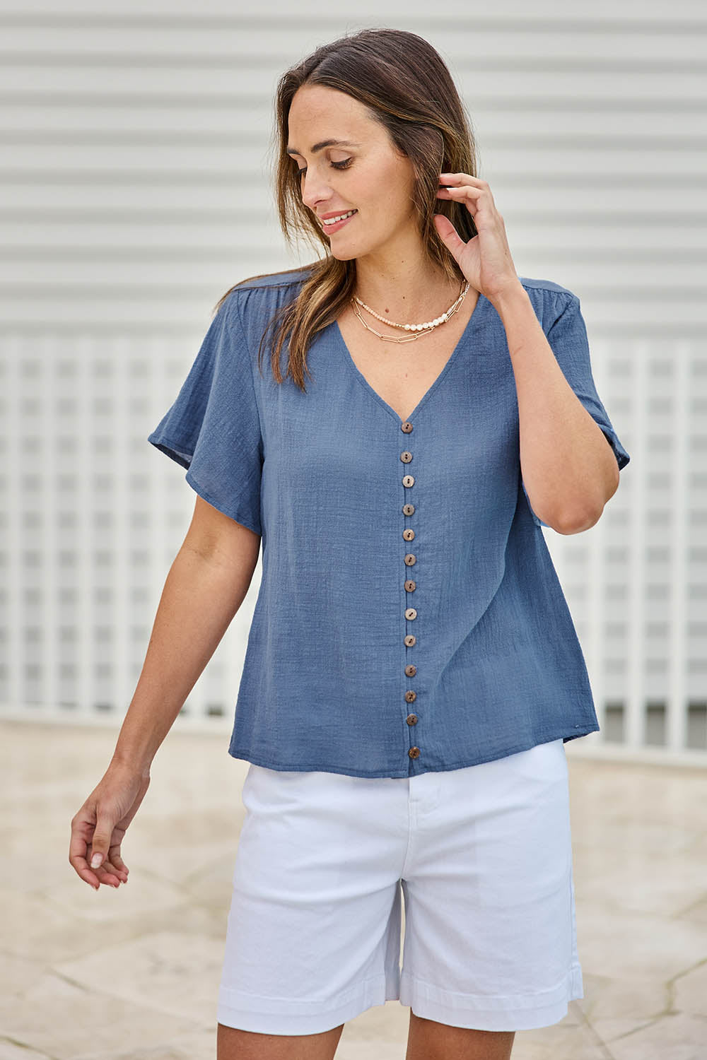 Model Tegand wearing size 10 of the Cute As A Button Blouse – Denim in colour Denim, in a cropped view