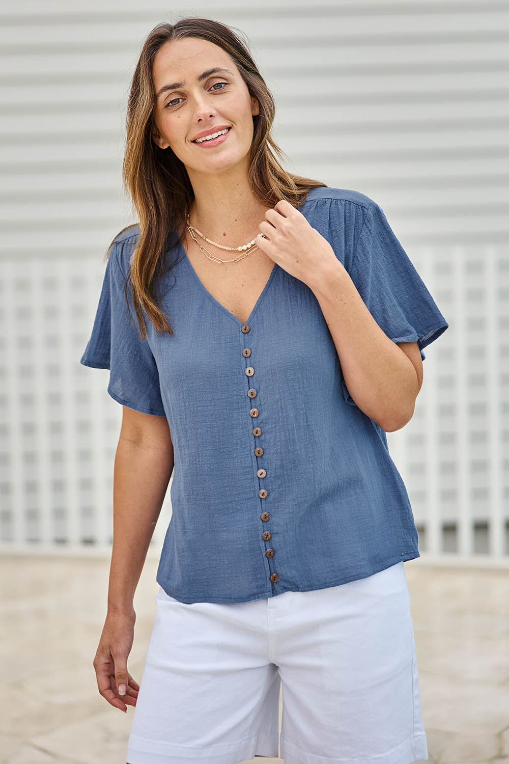 Model Tegand wearing size 10 of the Cute As A Button Blouse – Denim in colour Denim, in a cropped view
