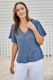 Model Tegand wearing size 10 of the Cute As A Button Blouse – Denim in colour Denim, in a cropped view