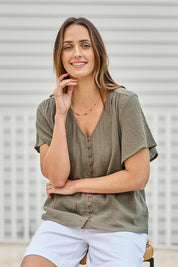 Model Tegand wearing size 10 of the Cute As A Button Blouse – Forrest in colour Forrest, in a cropped view