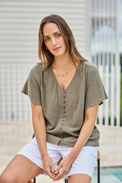 Model Tegand wearing size 10 of the Cute As A Button Blouse – Forrest in colour Forrest, in a cropped view