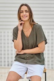 Model Tegand wearing size 10 of the Cute As A Button Blouse – Forrest in colour Forrest, in a cropped view