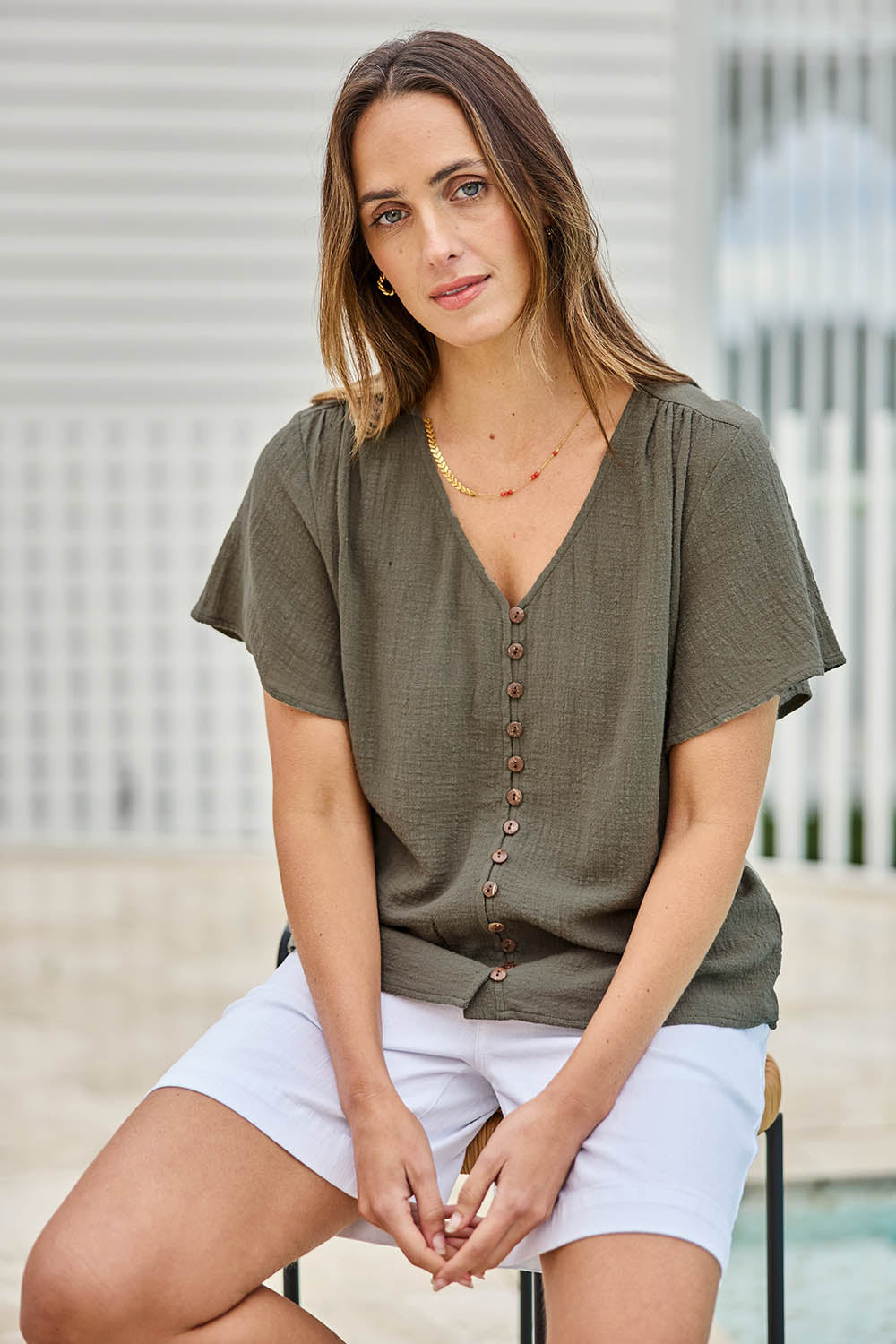 Model Tegand wearing size 10 of the Cute As A Button Blouse – Forrest in colour Forrest, in a cropped view