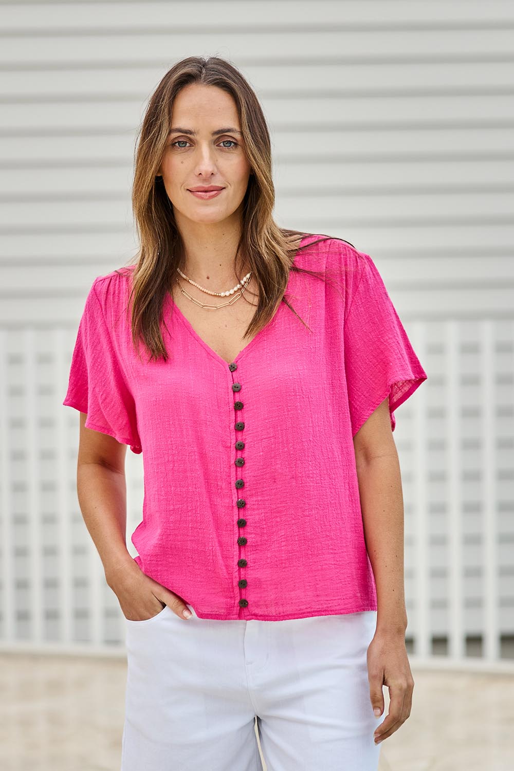 Model Tegand wearing size 10 of the Cute As A Button Blouse - Hotpink in colour Hotpink, in a cropped view