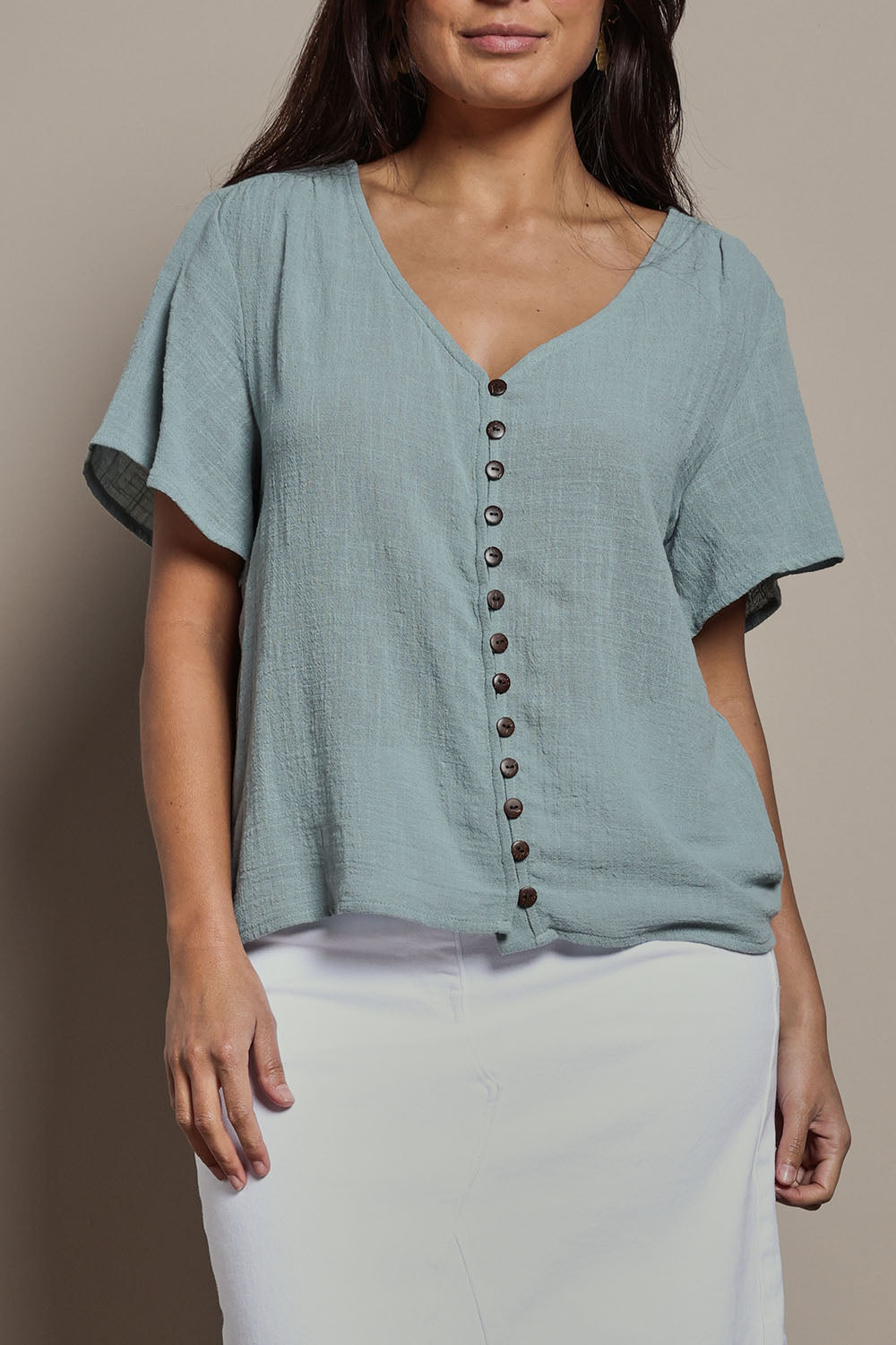Model Tahnee wearing size 10 of the Cute As A Button Blouse in colour Sage (Green), from the front, cropped image