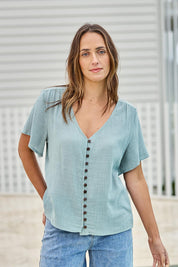 Model Tegand wearing size 10 of the Cute As A Button Blouse - Sage in colour Sage, in a cropped view