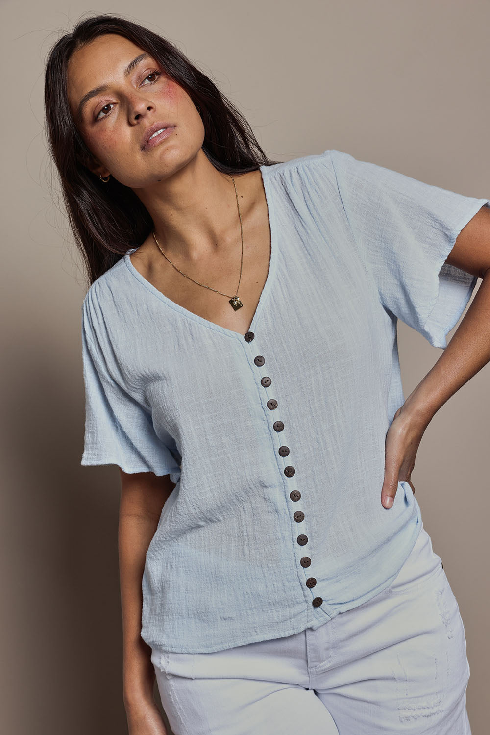 Model Tahnee wearing size 10 of the Cute As A Button Blouse in colour Sky (Blue), from the front, cropped image