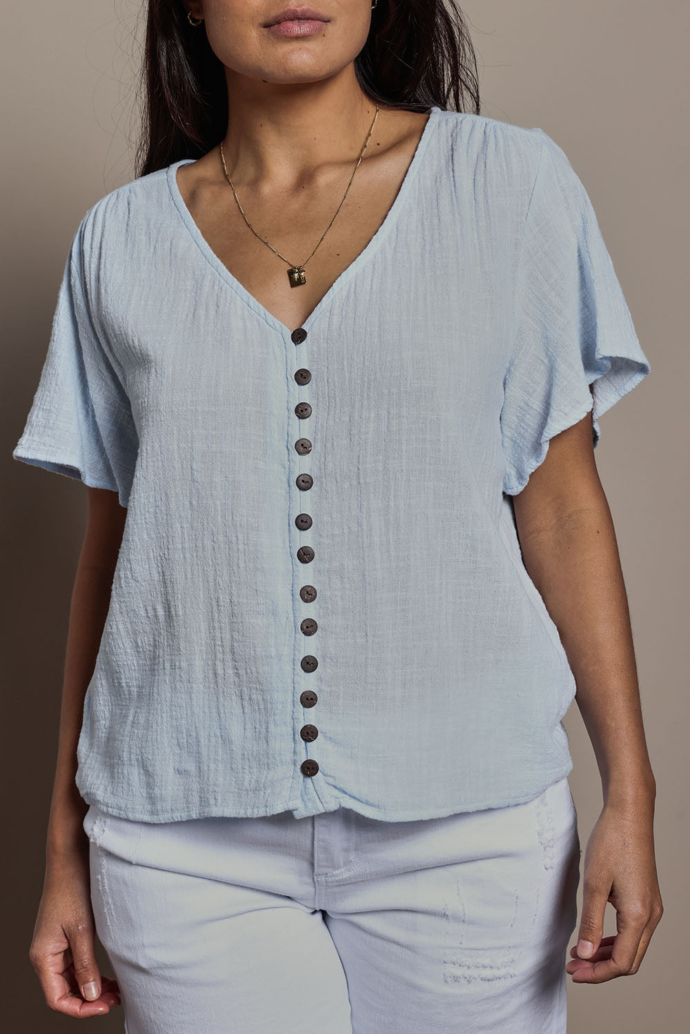 Model Tahnee wearing size 10 of the Cute As A Button Blouse in colour Sky (Blue), from the front, cropped image