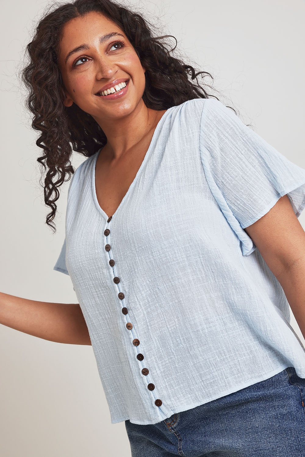 Model Terri-Leigh wearing size 14 of the Cute As A Button Blouse in colour Sky (Blue), from the front, cropped image
