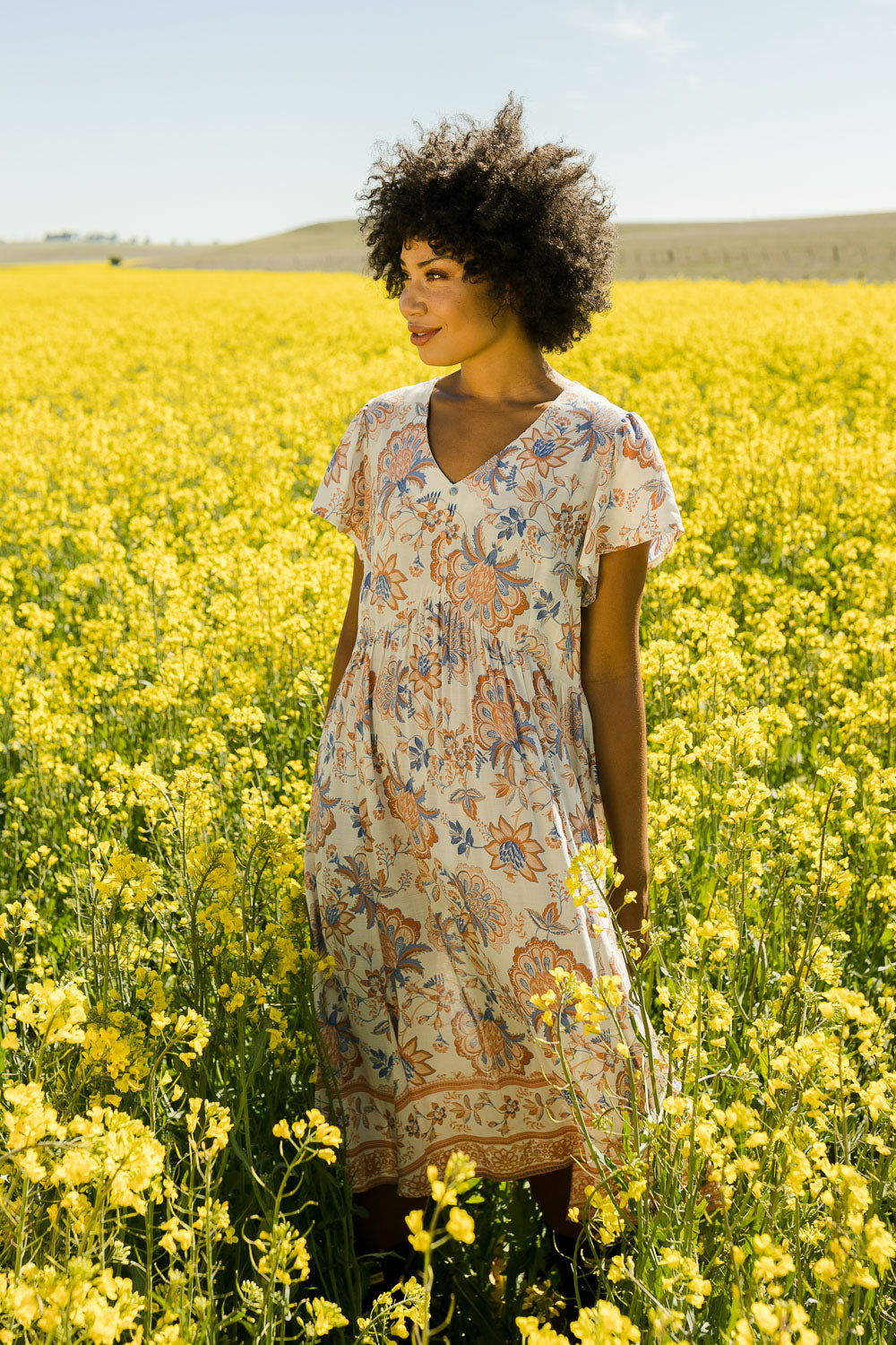 Model Olivia wearing size 10 of the Floating On By You Dress in colour Coralcream, from the front, showing the whole outfit