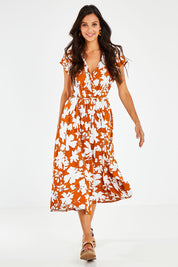 Model Vitoria wearing size 10 of the Feels Like Summer Wrap Dress in colour Rust, from the front, showing the whole outfit